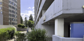 Concrete parking structure with exposed columns and paved courtyard in Timișoara, illustrating modern parking facilities where license plate recognition technology manages vehicle access.
