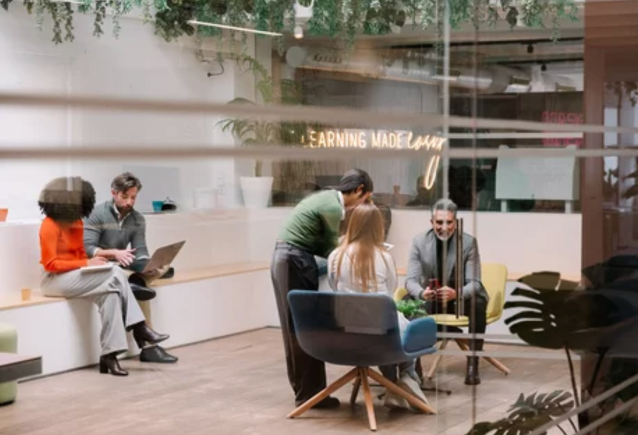Modern co-working office with people at laptops and contemporary furniture, illustrating the digital workspace environment where online business directories are accessed and utilized.