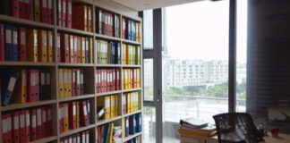 Modern office with floor-to-ceiling shelves holding colorful organized binders and folders, representing systematic categorization used in industry-specific business directories.