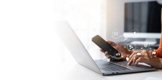 Multichannel Marketing Without Directories Is Half-Done Person using laptop and smartphone at desk with digital marketing icons overlaid, representing coordinated multichannel marketing strategy across business platforms.