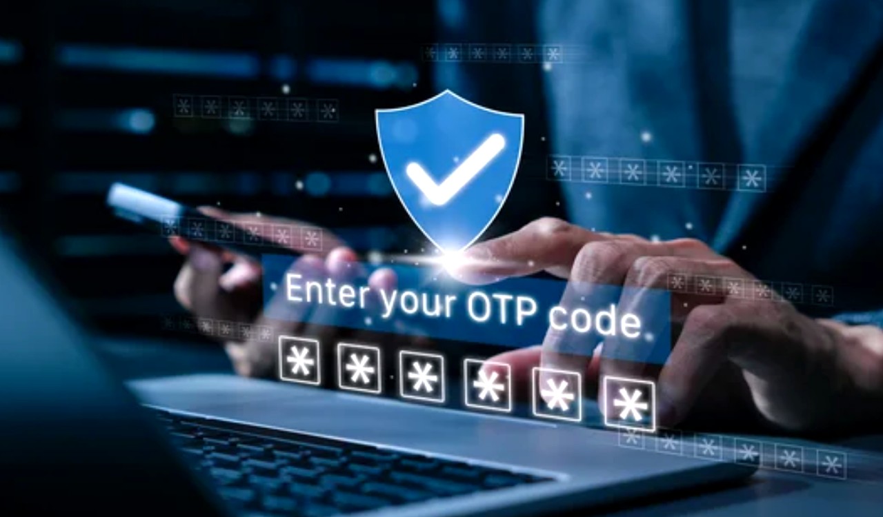 Hands typing on laptop with holographic blue shield and OTP entry interface overlaid, representing digital authentication methods for business verification systems.