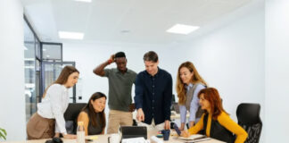 From Niche to Go-To Authority: The Blueprint for Building a Community-Based Directory Six diverse professionals collaborate around a conference table in a bright modern office, demonstrating the teamwork essential for building community-based directory platforms.