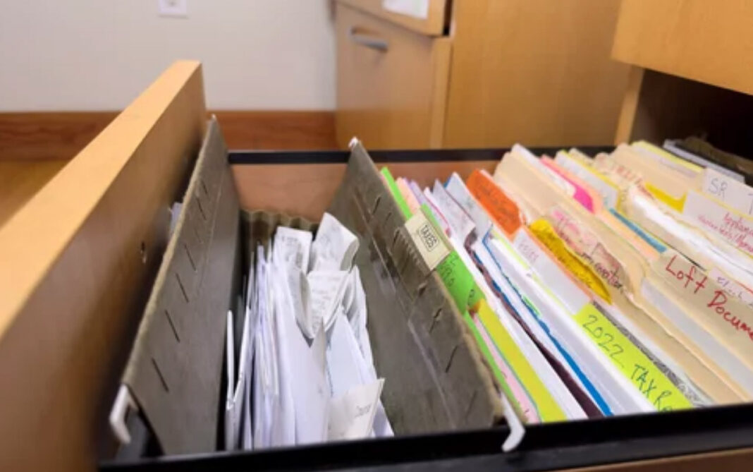 Organized filing system illustrates systematic approach to business directory management Open filing drawer with organized documents, colored folders, and gray dividers demonstrating systematic organization methods applicable to business directory structures.
