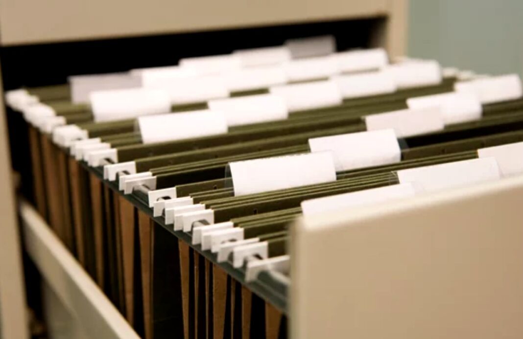 Organized filing system illustrates the structured approach smart marketers use with curated directories White tab dividers organize green hanging folders in a wooden filing drawer, representing the systematic curation and categorization approach used in effective business directories.