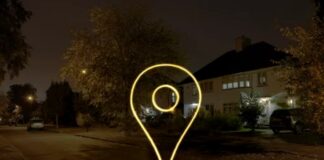 Glowing yellow location pin icon illuminated above a suburban residential street at night, representing the geolocation technology behind local search optimization.