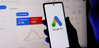 Display Ads Failing? Add Directory Citations First Hand holding smartphone with Google Ads logo in front of desktop monitor displaying advertising dashboard metrics, representing display advertising tools discussed in directory citation strategy.