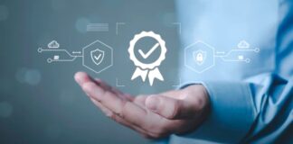 Hand in business attire presented beneath floating digital security icons, certification badges, and shield symbols, representing business verification and fraud prevention measures.