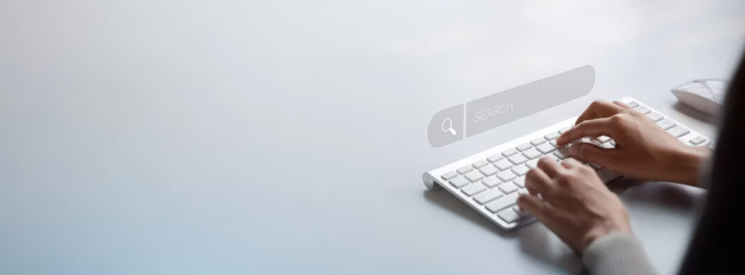 Digital search interface and keyboard typing illustrate AI-powered keyword research workflows Hands typing on a white keyboard with a translucent search bar overlay, illustrating the digital interface used in AI-driven keyword research processes.