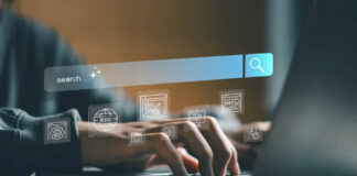 Hands typing on laptop keyboard with translucent digital overlay showing search bar and SEO icons, illustrating web rendering and search optimization concepts.
