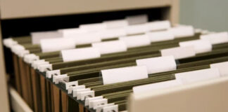 Olive-green hanging file folders with white tabs organized in a drawer, symbolizing the systematic approach to selecting and categorizing business directory listings.