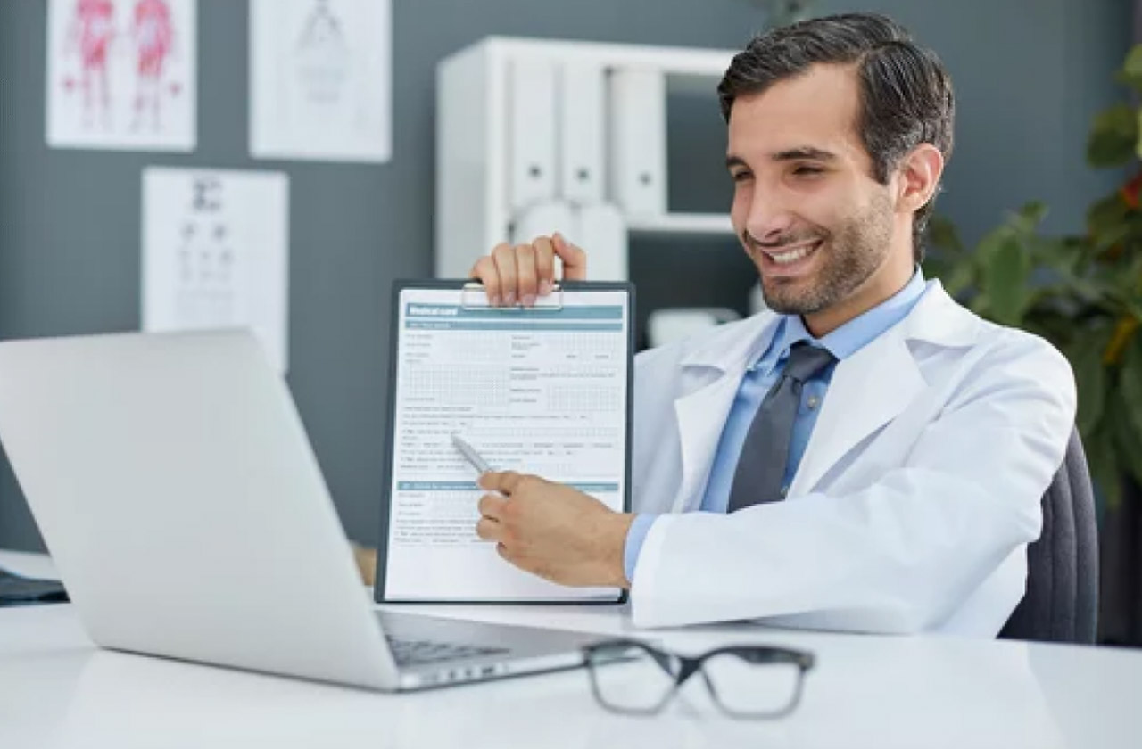 Healthcare professional in white coat points to medical form on clipboard at desk with laptop, illustrating simplified registration and listing processes.
