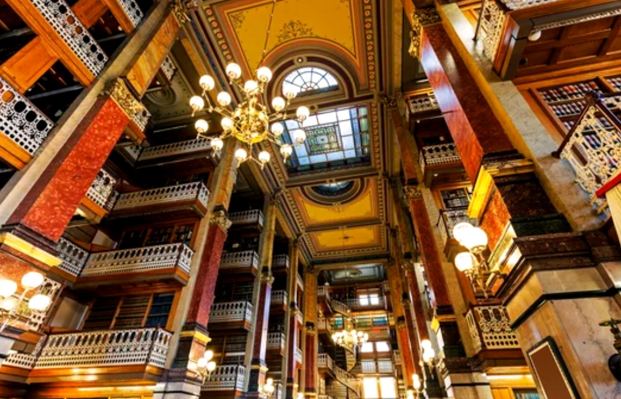 Grand multi-story atrium with stained glass skylight and ornate balconies, exemplifying the historic architecture that enhances art appreciation in cultural institutions.