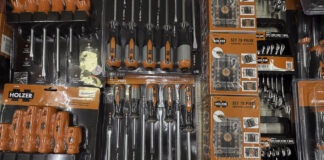 Packaged HOLZER tool sets displayed on retail shelving in a hardware store, illustrating how local retailers organize products for customer discovery and selection.