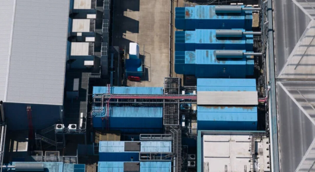 Industrial infrastructure underpins commercial directories growth in Asian megacities Aerial view of industrial facility with blue corrugated rooftops and ventilation equipment, representing the commercial infrastructure that supports business directories in metropolitan markets.