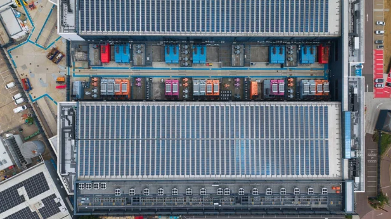 Aerial photograph of industrial warehouse rooftop with extensive solar panel installation and modular equipment, representing sustainable commercial infrastructure supporting business growth in Asian metropolitan markets.