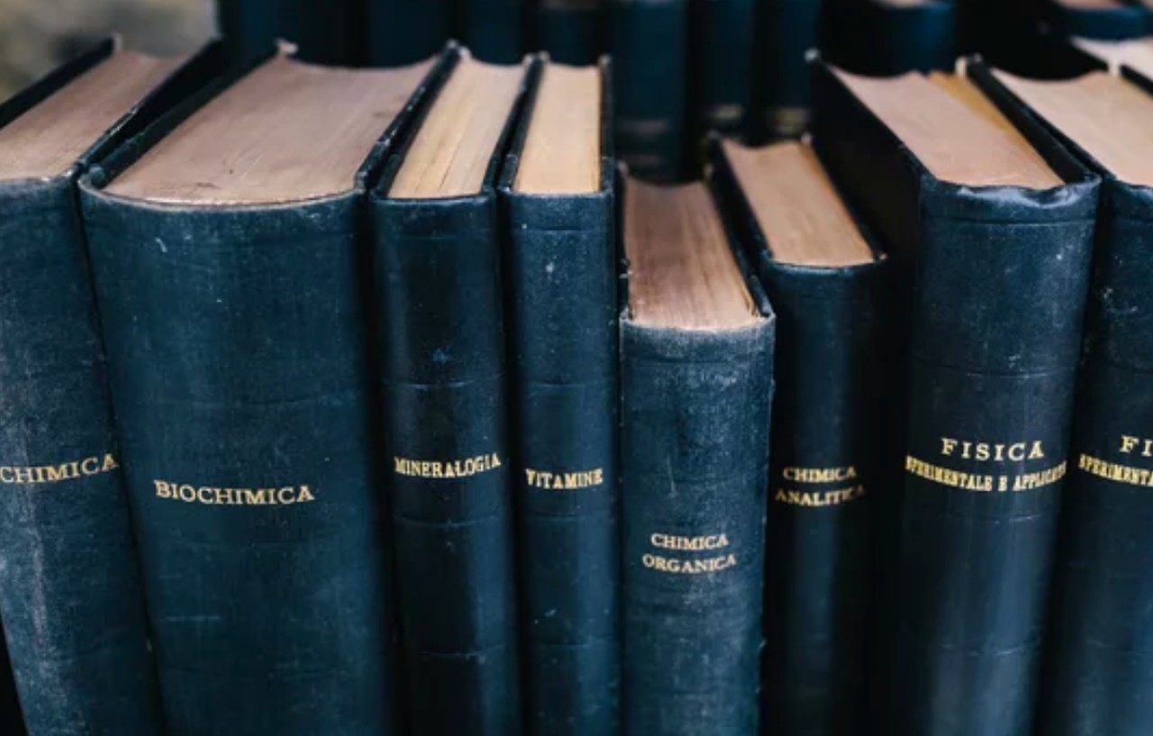 Dark blue hardcover scientific textbooks with Italian titles arranged on a library shelf, representing the systematic organization of academic resources in subject directories.