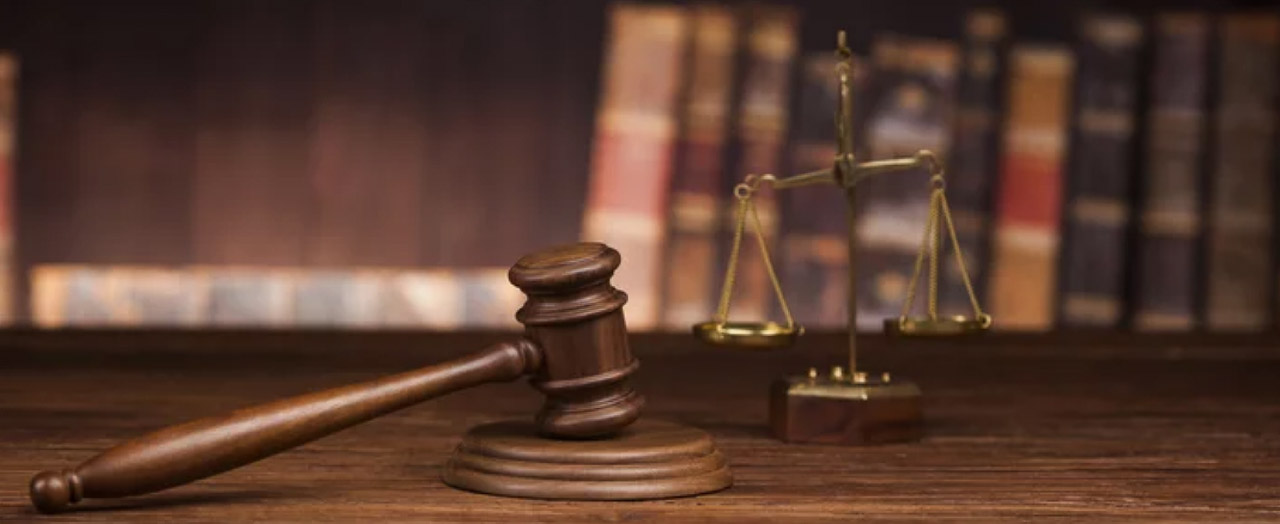 A wooden judge's gavel and brass scales of justice rest on a dark wooden desk with law books in the background, symbolizing the authority and trust signals central to law firm SEO.