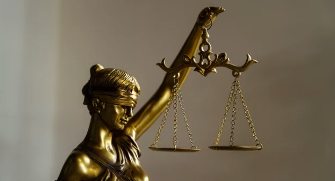 Brass Lady Justice statue holding raised scales with blindfold, representing ethical standards and fairness in law firm marketing practices.