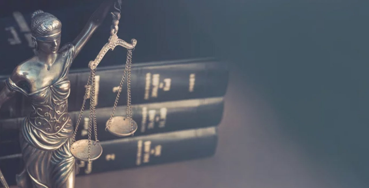 Lady Justice statue holding balanced scales stands before stacked law books, symbolizing the demonstration of legal expertise and authority in professional content.
