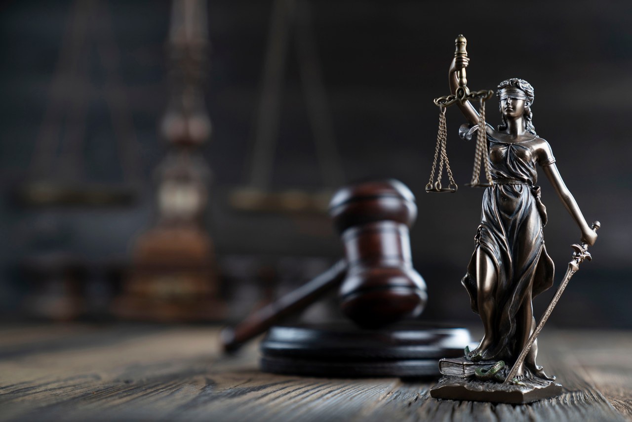 Lady Justice statue holding scales and sword beside a wooden gavel, symbolizing the impartiality and authority central to criminal defense representation.