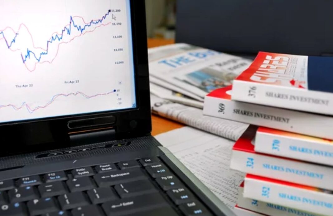 Tracking directory ROI through financial analytics and performance measurement tools Laptop displaying financial line graphs sits beside investment books on a desk, illustrating analytics tools for measuring Canadian directory marketing ROI.