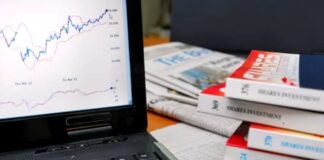 Track Canadian Directory ROI Like a Pro Laptop displaying financial line graphs sits beside investment books on a desk, illustrating analytics tools for measuring Canadian directory marketing ROI.