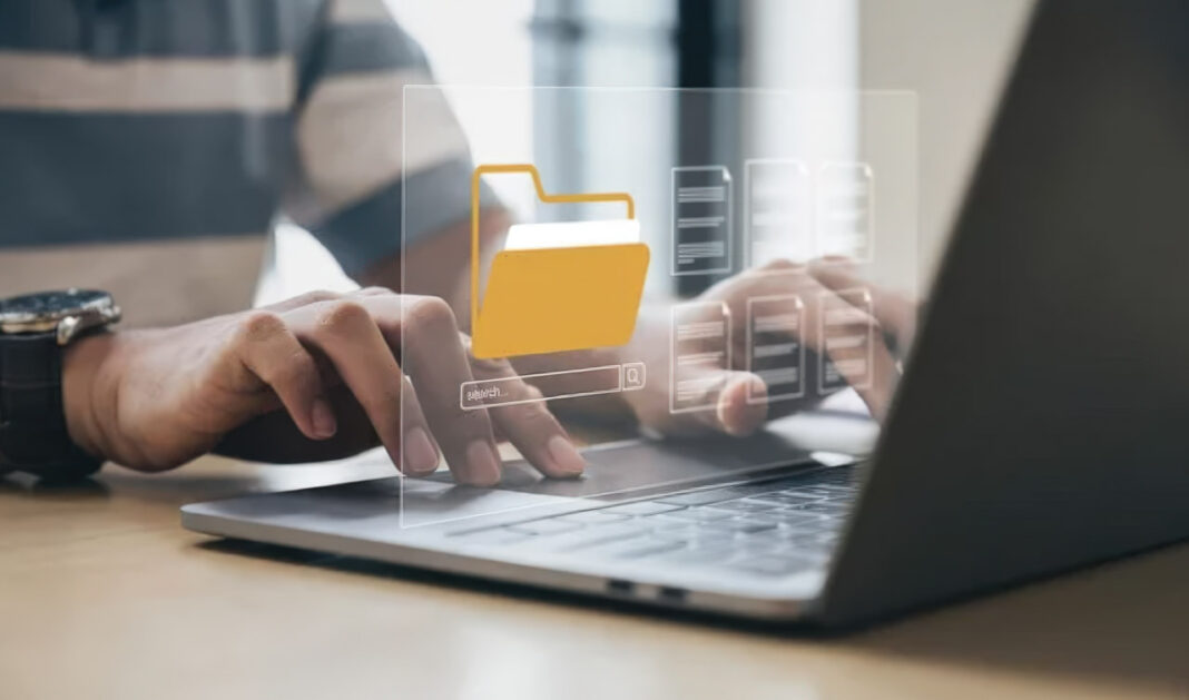 laptop-users-folder-search-overlay-digital-workspace-office-directories Two people work on a laptop with a yellow folder icon and search bar overlay, illustrating digital organization methods used by SEO professionals to manage directory listings.