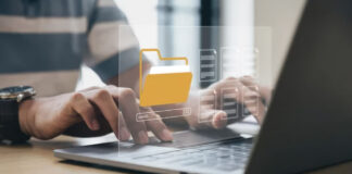 How SEO Pros Use Directories for AI Search Visibility Two people work on a laptop with a yellow folder icon and search bar overlay, illustrating digital organization methods used by SEO professionals to manage directory listings.