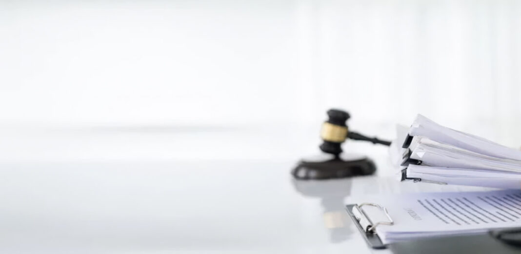 Legal office supplies symbolizing the professional credibility essential for law firm directory listings Wooden gavel and stacked legal documents with binder clips on white desk, representing the professional foundation of law firm directory presence.