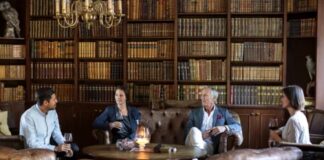 A Name in a Report Is Not a Verdict: How to Read Clergy Abuse Records Four guests gather around a table in a traditional library with floor-to-ceiling bookshelves, illustrating the welcoming atmosphere that helps travel businesses attract direct bookings.