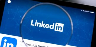 How to Choose a Domain Name That Fits Today’s Brand and Tomorrow’s Business Magnifying glass held over a tablet displaying the LinkedIn app interface with logo and job search text, representing professional networking tools used in link building strategies.