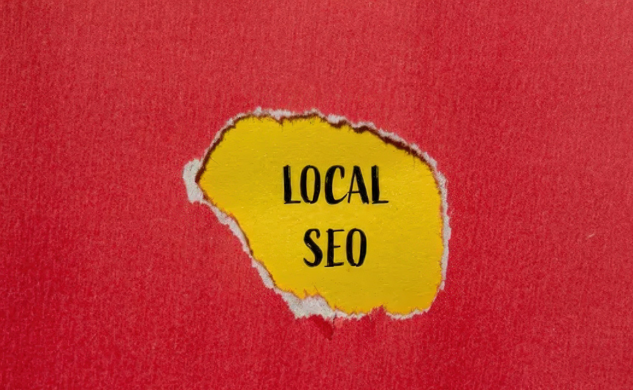 Torn yellow paper reveals 'LOCAL SEO' text on red background, representing the visibility and discovery businesses gain through directory citation sources in AI search.