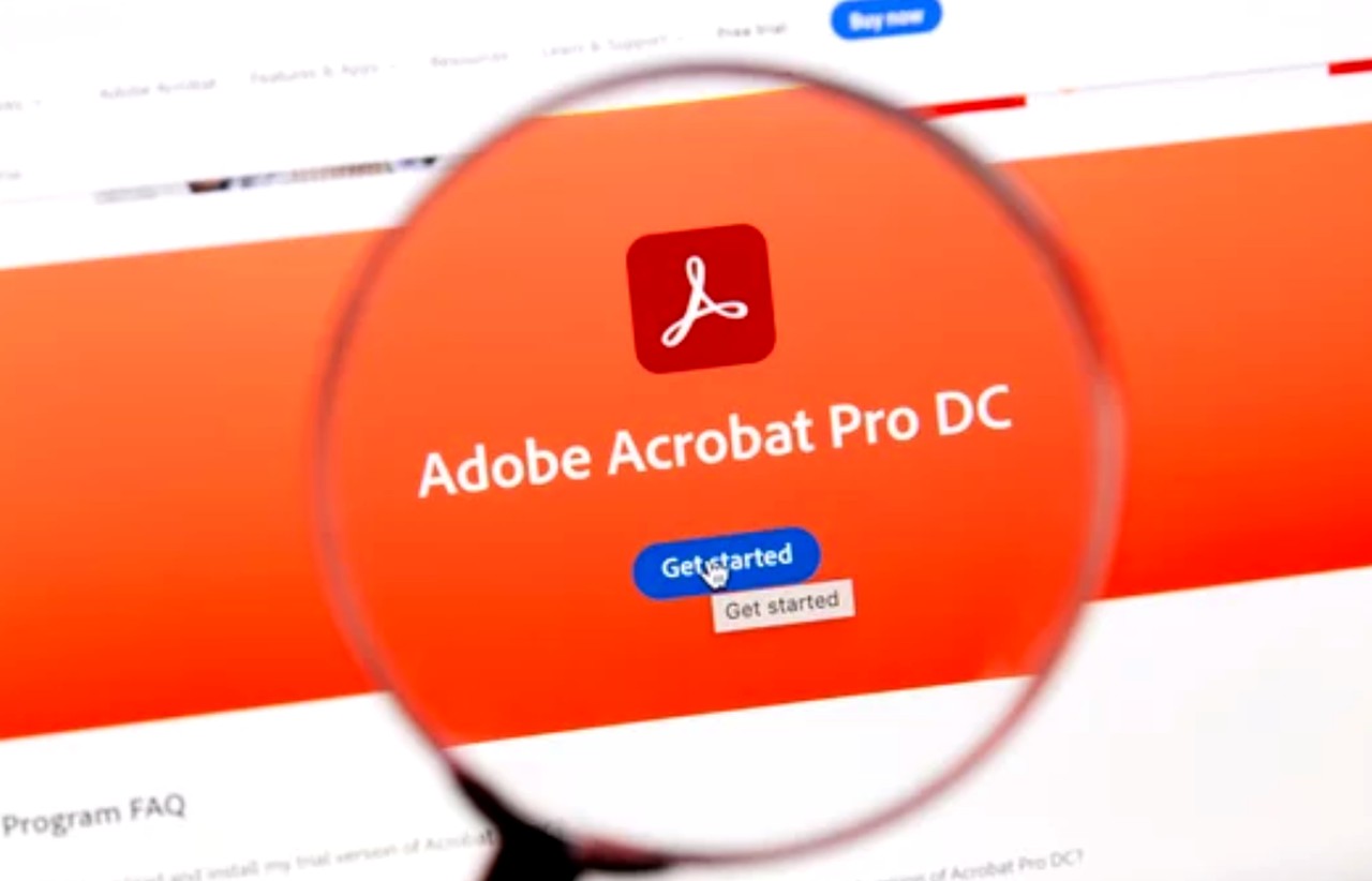 Magnifying glass positioned over Adobe Acrobat Pro DC software interface on a computer screen, illustrating PDF software options for small businesses.