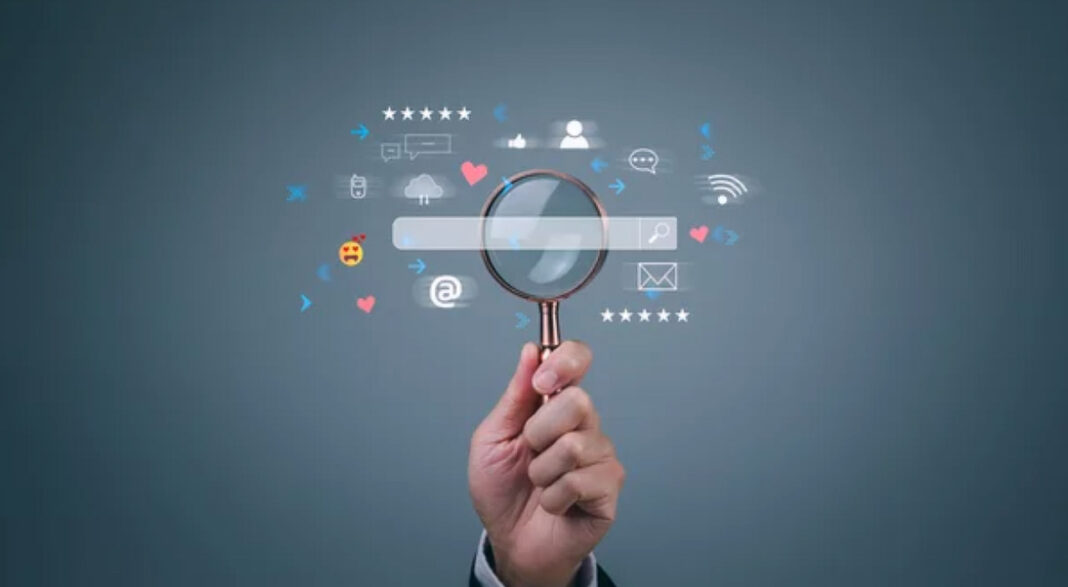 Digital search investigation illustrates the importance of accurate business citations for AI search visibility Hand holding magnifying glass over digital search bar with floating social media icons, representing the careful examination needed to avoid citation mistakes in business listings.