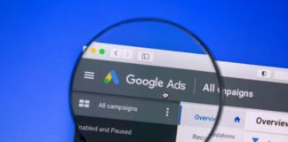 A magnifying glass focuses on a Google Ads interface displayed on a computer screen, symbolizing the scrutiny and optimization required for visual search advertising campaigns.