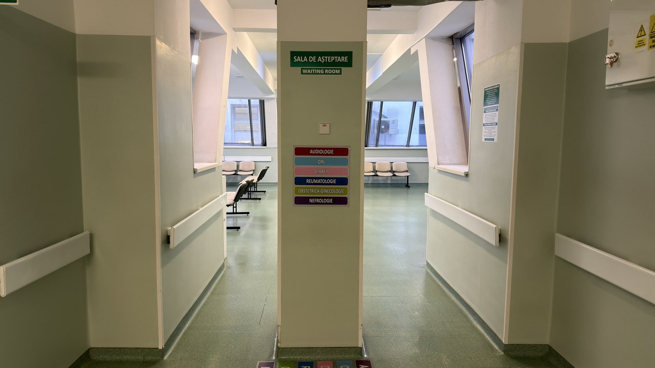 Medical facility corridor with central directional signage pillar and waiting areas, illustrating the wayfinding infrastructure that enhances patient experience in modern outpatient clinics.