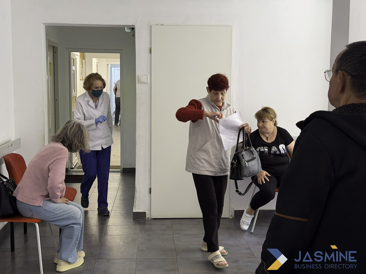 Healthcare workers in white coats and masks attend to patients in a medical waiting room, representing the walk-in clinic model of immediate care.