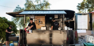 How Small Business Owners Can Build a Budget That Actually Works Black mobile food trailer with burger signage and two staff members serving customers, exemplifying a mobile business that operates without a traditional storefront location.