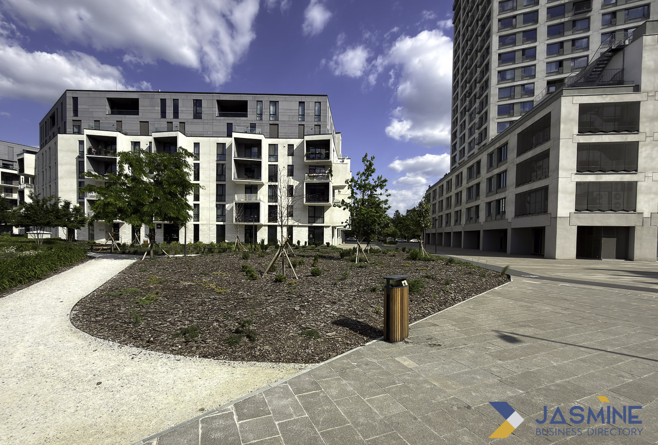 Modern apartment buildings surround a landscaped courtyard with young trees and paved pathways, illustrating neighborhood-specific property content for real estate SEO strategies.