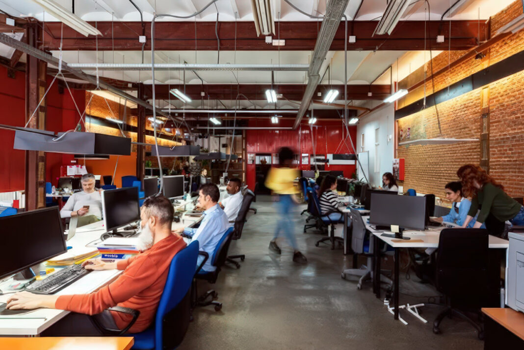 Modern office workspace illustrating professional environment for discovering Australian business directories and competitive intelligence tools Open-plan office with employees working at computer workstations under industrial ceiling, representing the professional environment where businesses conduct directory research and competitive analysis.