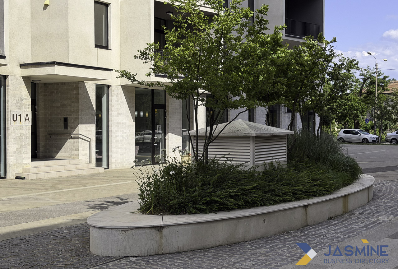 Modern residential building entrance with curved planter containing trees and ornamental grasses, illustrating professional landscaping that improves property appearance and outdoor spaces.
