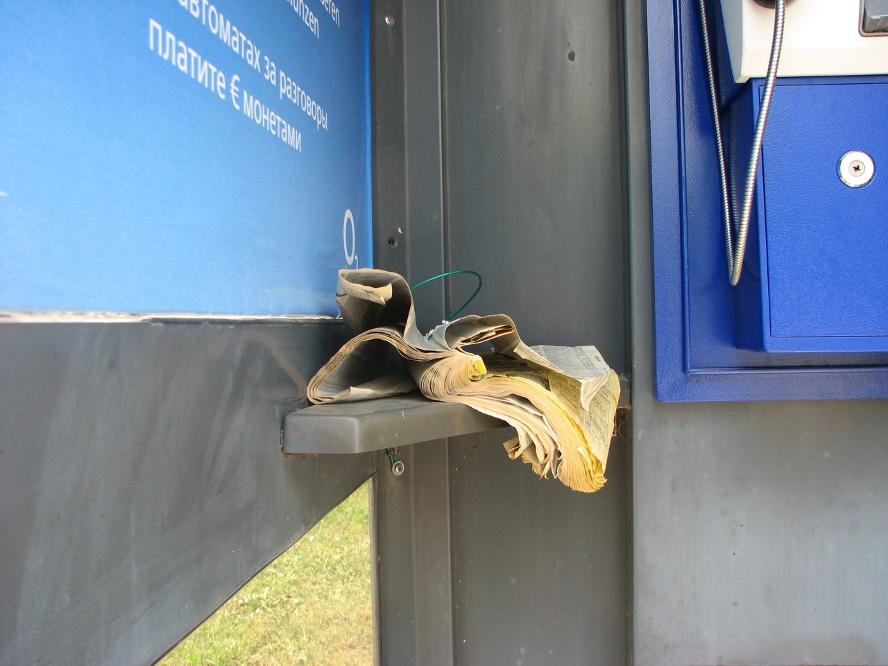 A worn mop resting on a service station shelf beneath a Cyrillic payment panel, representing the maintenance services once discovered through printed business directories.