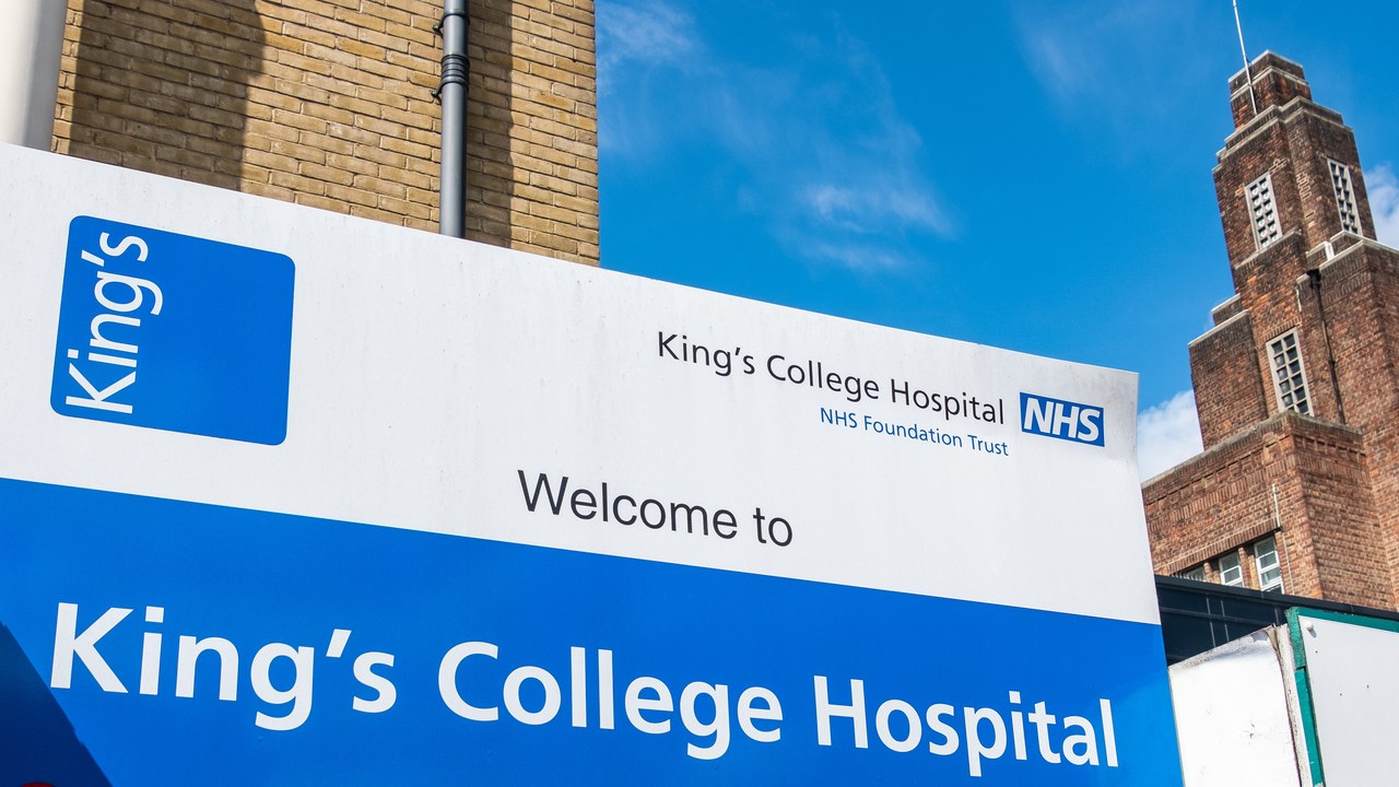 NHS hospital entrance sign for King's College Hospital with brick clock tower, representing healthcare facility visibility crucial for physician directory listings and patient acquisition.