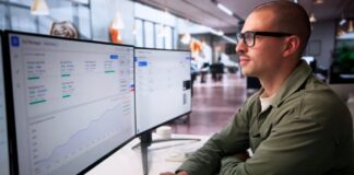 Professional wearing glasses works at dual-monitor workstation displaying analytics dashboards in modern office, illustrating how SEO specialists adapt to AI-driven changes in digital marketing.