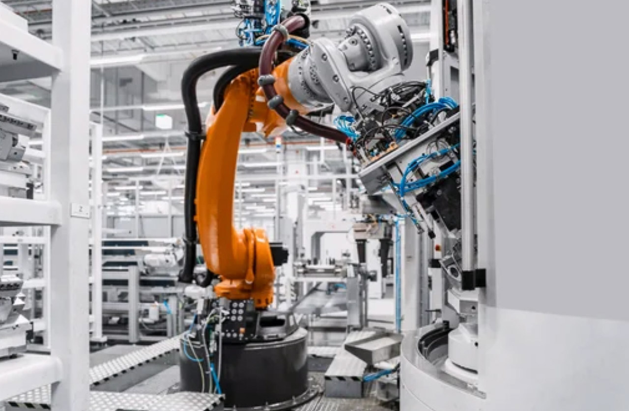 Orange robotic arm holding metal component in modern manufacturing facility, illustrating the type of industrial equipment suppliers featured in specialized business directories.