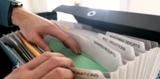 Why Paying Off Personal Debt Should Be Part of Your Entrepreneurial Plan Hands organizing labeled financial documents in an accordion folder on a desk, representing the systematic categorization required for multi-faceted directory monetization models.
