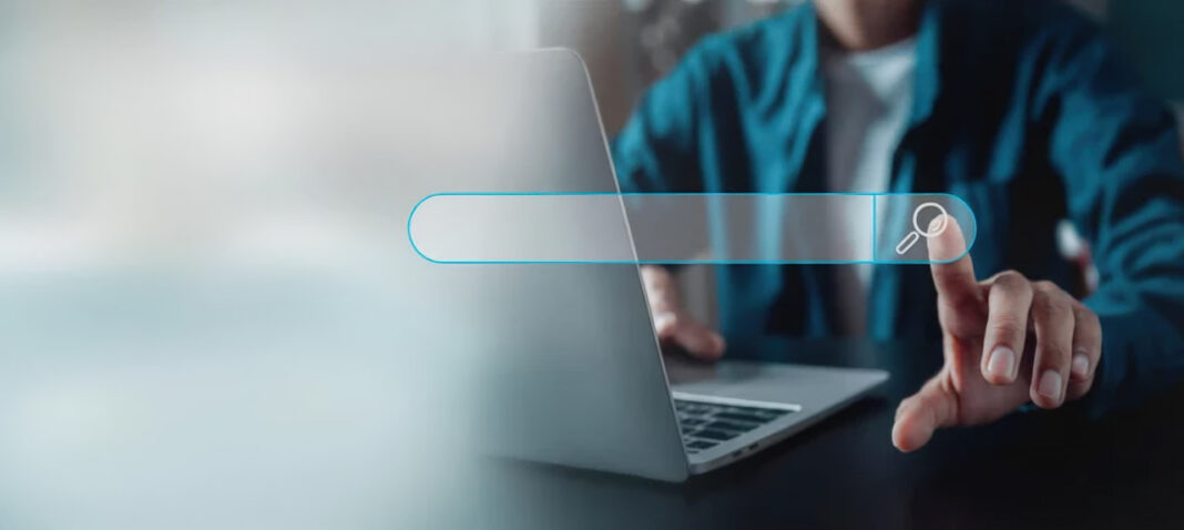 person-demonstrating-digital-search-bar-interface-laptop-business-directory-technology Person in teal clothing points to a floating digital search bar above a laptop, illustrating the modern interface of business directory services.