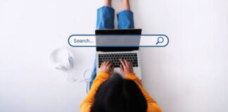 Why You’re Not Showing Up Online (and 50 Directories to Fix It) Overhead view of person typing on laptop with search bar overlay graphic, representing the process of searching for businesses online and directory optimization.