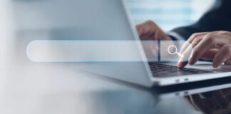 The Psychology of Search: What Users Really Want When They Query AI Close-up of hands typing on laptop keyboard with translucent search bar overlay, illustrating user behavior when formulating search queries.
