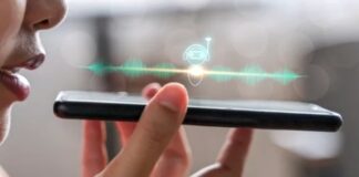 Person holds smartphone displaying voice assistant interface with robot icon and green waveform, illustrating voice-based answer engine optimization technology.